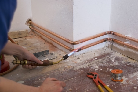 Man braising copper pipes in home